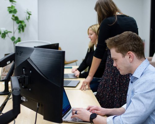 Digital marketing specialists working on their laptops side by side at the Anchor Wave office